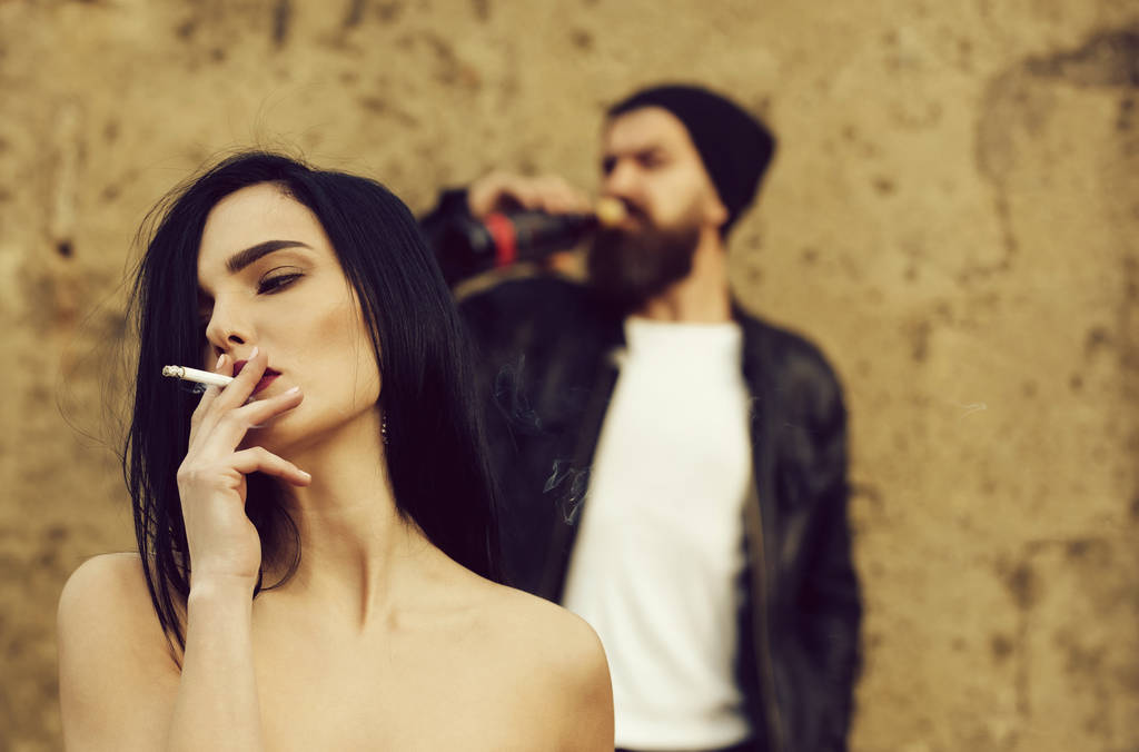 Mädchen raucht Zigarette und verschwommener Mann trinkt Hipster aus Flasche - Foto, Bild