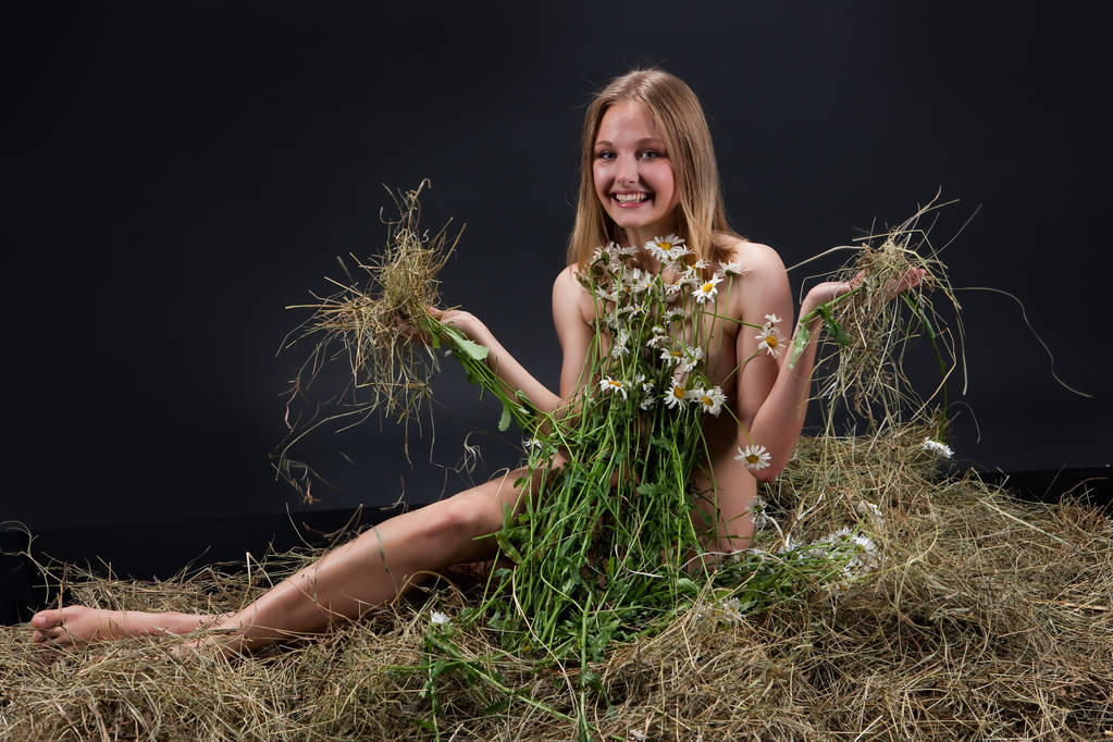 Jeune femme nue avec des fleurs sur un foin dans le studio
 - Photo, image