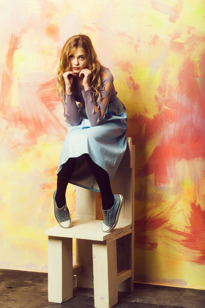 Güzel kız mavi etek ve spor ayakkabılar üzerinde ahşap sandalye - Fotoğraf, Görsel