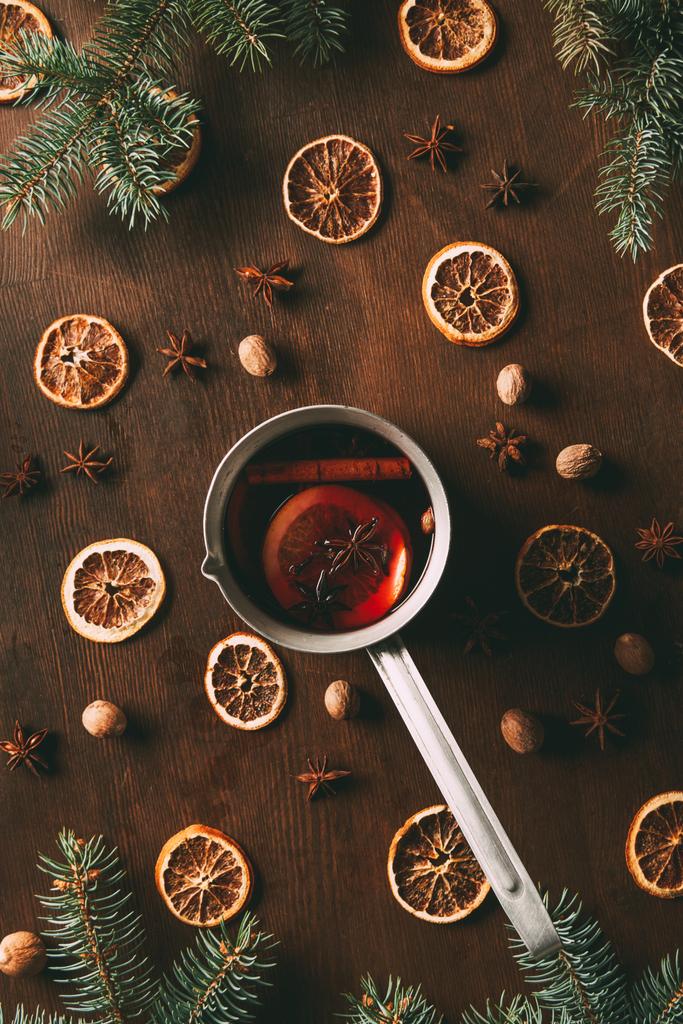 松の枝で木製の背景に乾燥オレンジ スライスと鍋にホット スパイス ワインのトップ ビュー - 写真・画像
