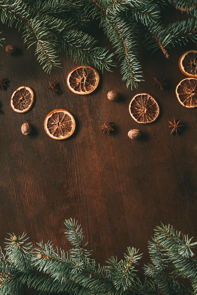 Horní pohled na vánoční koření na dřevěném pozadí s jedlovými větvemi a kopírovacím prostorem - Fotografie, Obrázek