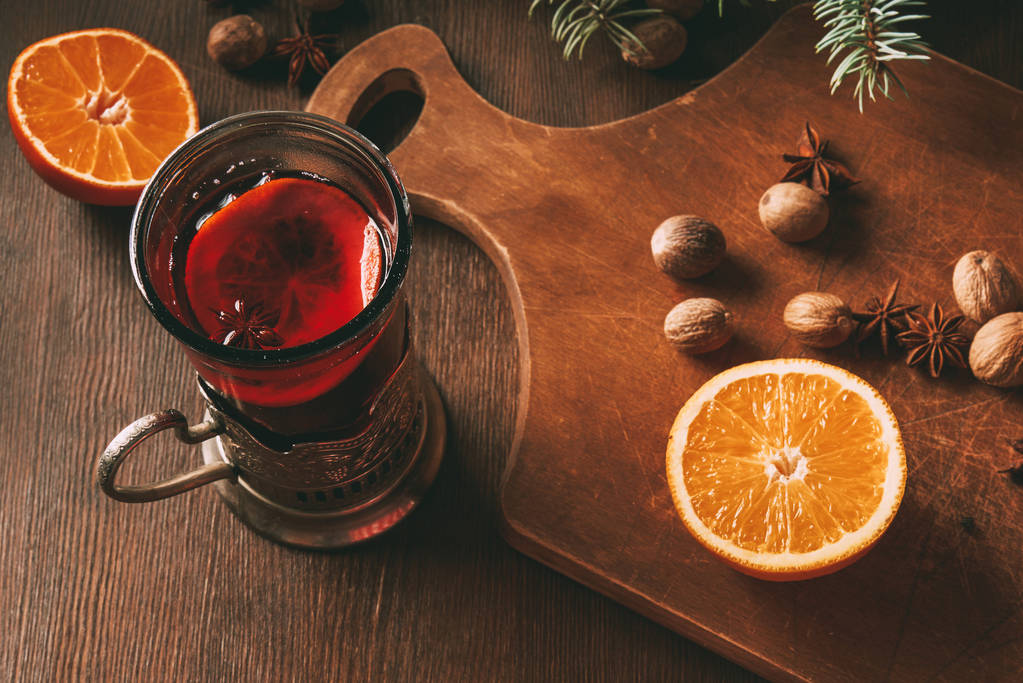 forró forralt bor, fűszerek és a narancs az üveg csésze, fából készült háttér - Fotó, kép