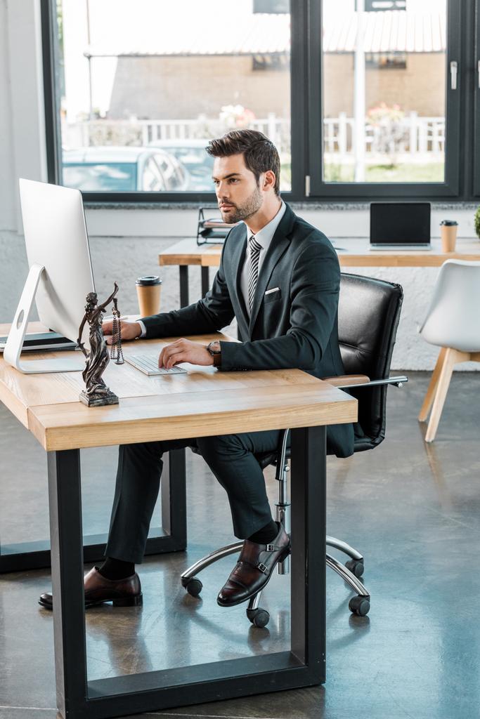 pohledný právník pracující s počítačem u stolu v kanceláři - Fotografie, Obrázek
