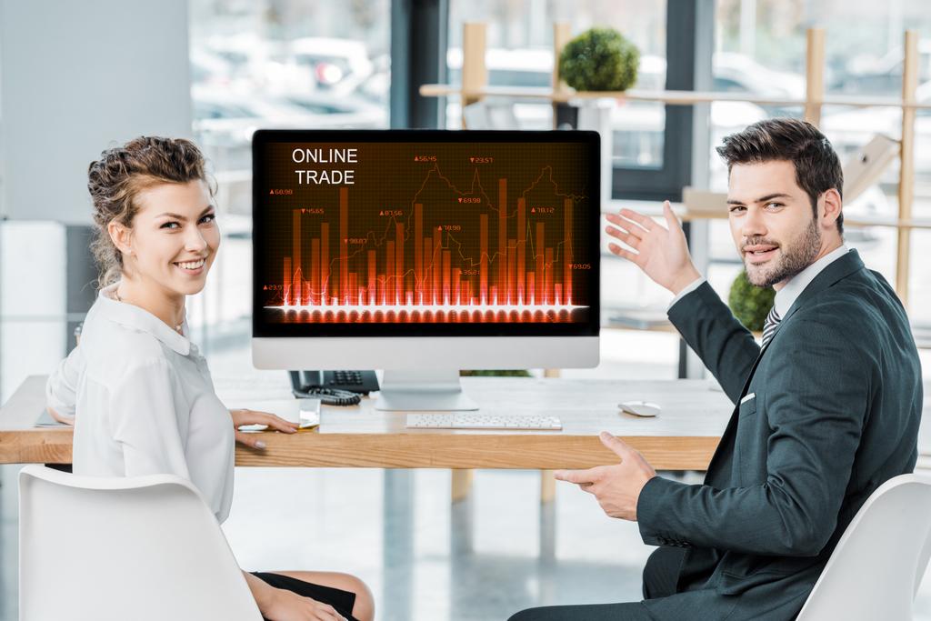 uśmiechający się współpracownikami w miejscu pracy z ekranem komputera z handlu internetowego napis w biurze - Zdjęcie, obraz