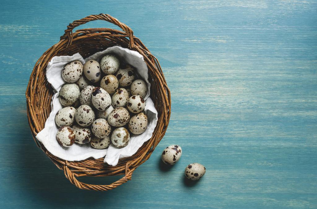 vista superior de huevos de codorniz crudos y sanos en canasta de mimbre sobre mesa de madera turquesa
  - Foto, imagen