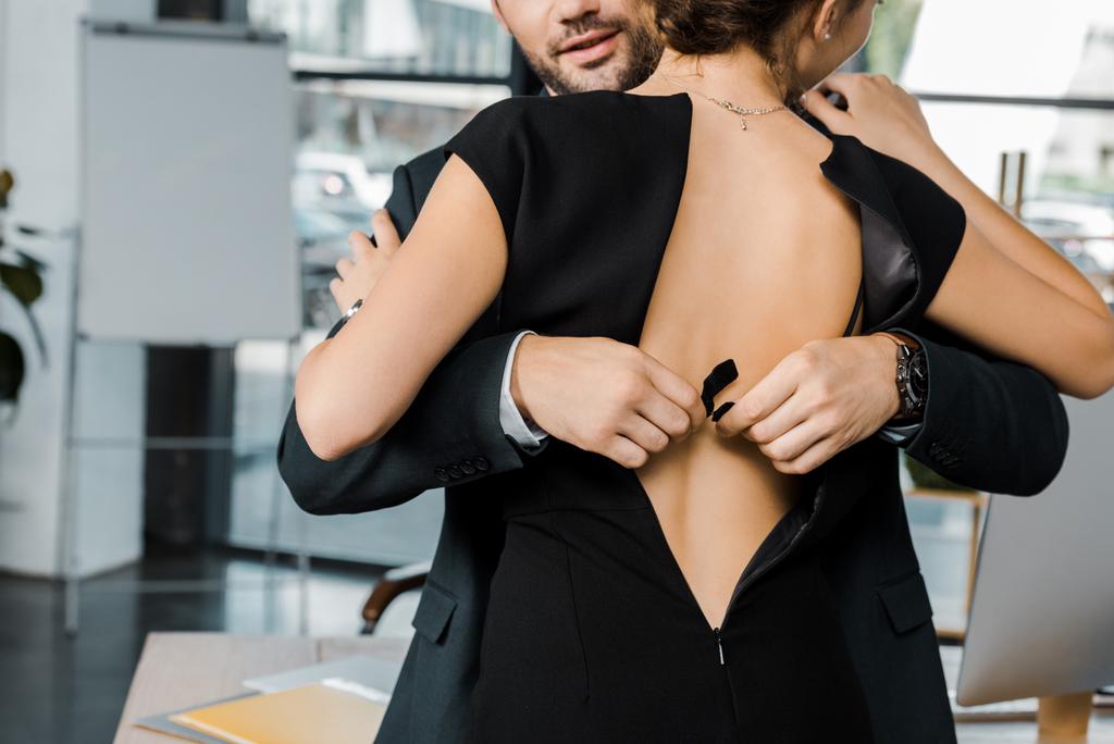 partial view of businessman unbuttoning bra of businesswoman in office - Photo, Image