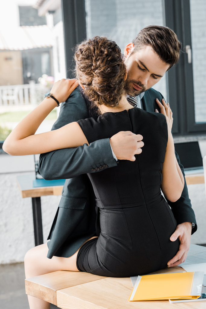 passionate businessman unzipping dress of seductive businesswoman at workplace in office - Photo, Image