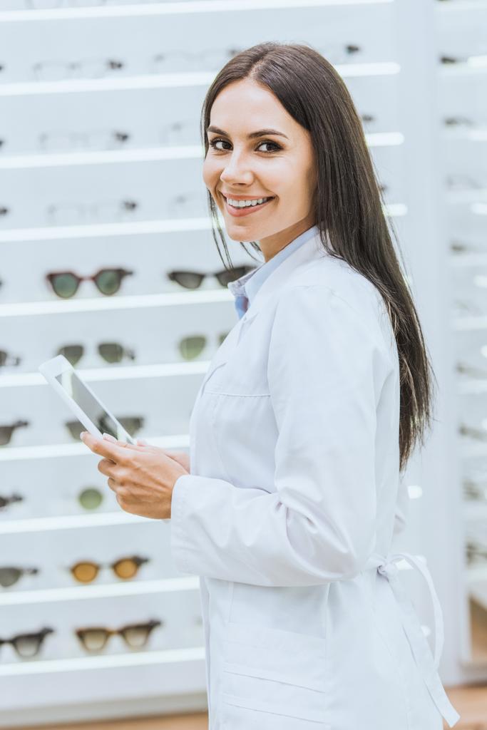усміхнений оптик використовує цифровий планшет на роботі в офтальмологічному магазині
 - Фото, зображення