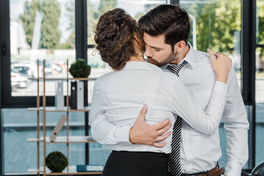 passionate business colleagues in formal wear hugging in office - Photo, Image
