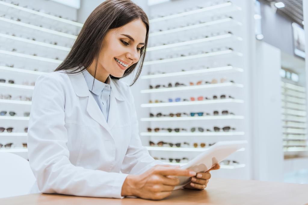 professional smiling optician using tablet in optica - Photo, Image