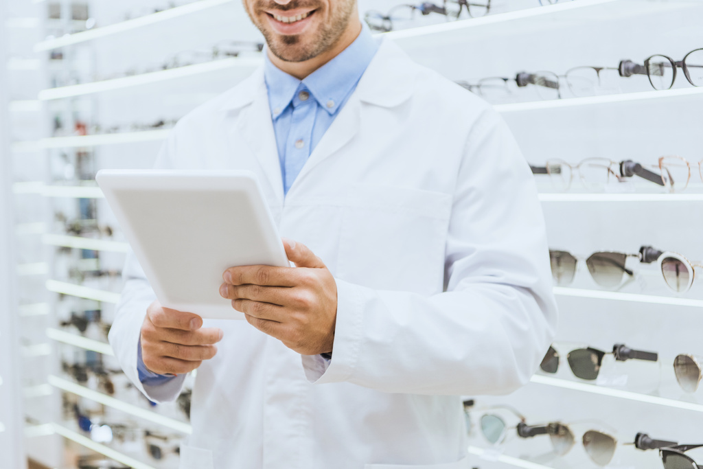 Dijital tablet optica içinde kullanma Beyaz paltolu optometrist görünümünü kırpılmış - Fotoğraf, Görsel