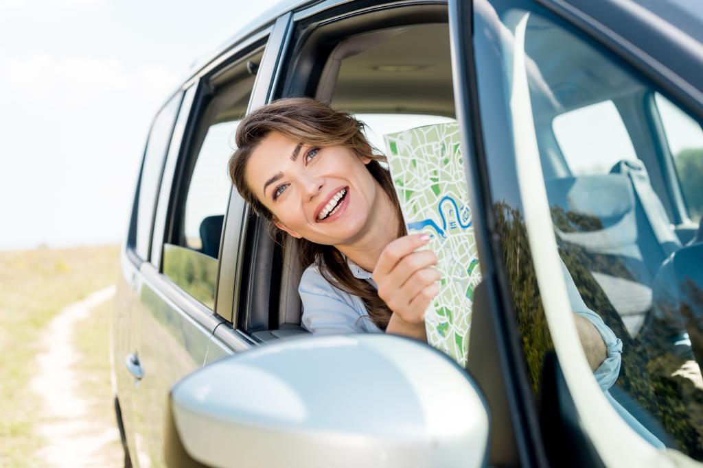 красивая счастливая женщина с картой проезда внутри автомобиля в поле
 - Фото, изображение