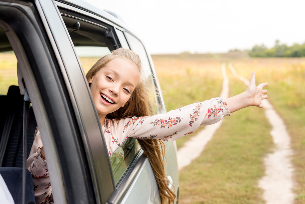 szczęśliwe dziecko mało patrząc z okna samochodu podczas jazdy przez pola - Zdjęcie, obraz