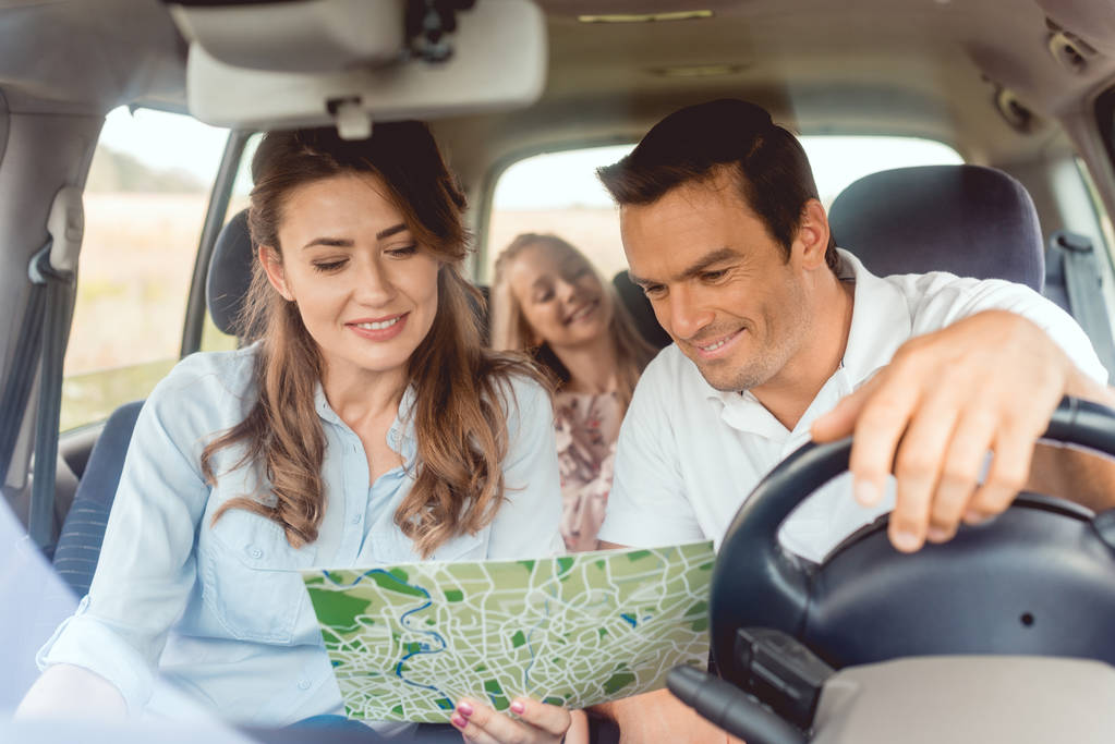 красивая семья смотрит на карту вместе во время поездки на машине
 - Фото, изображение