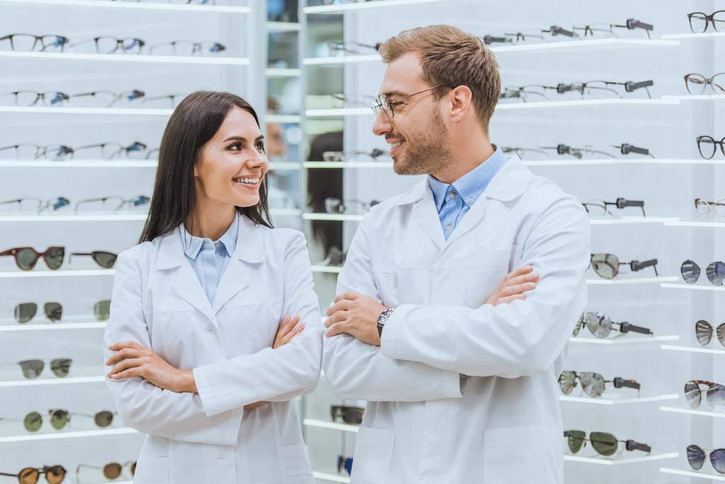 médicos sorridentes profissionais posando com braços cruzados na loja oftálmica com óculos
 - Foto, Imagem