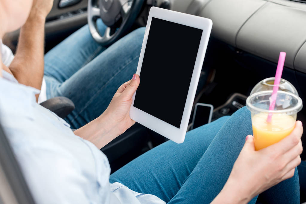 女性の車でタブレットを使用してオレンジ ジュースのプラスチックのカップでのクロップ撮影 - 写真・画像
