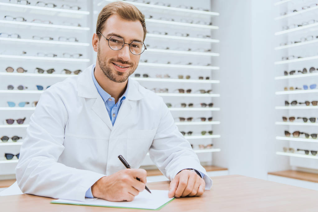 professional optometrist writing diagnosis in ophthalmic shop - Photo, Image
