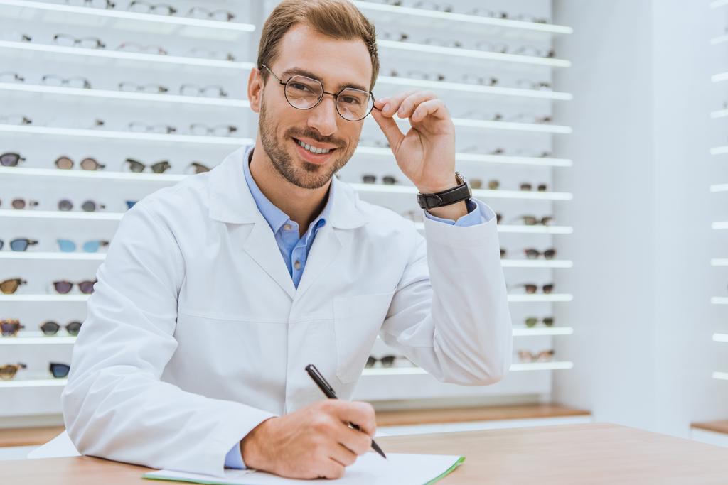 profesjonalny lekarz w białym płaszczu pisania diagnozy w optica - Zdjęcie, obraz