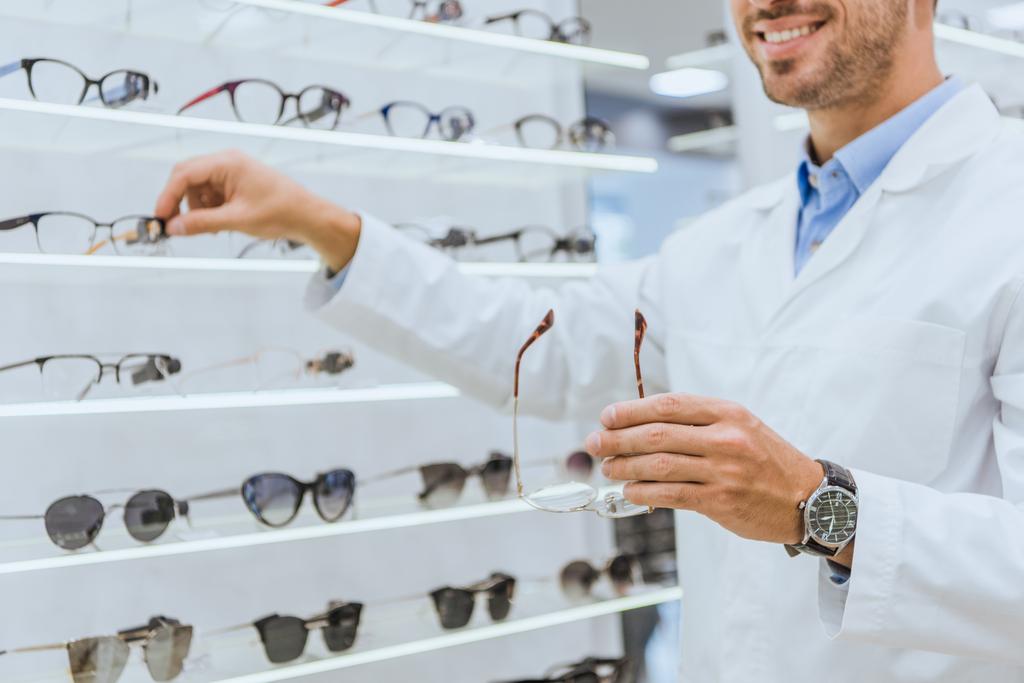 vue recadrée de l'optométriste prenant des lunettes des étagères dans un magasin d'ophtalmologie
 - Photo, image