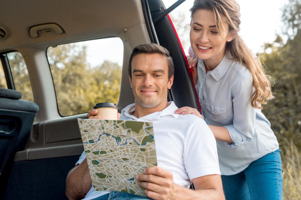 車で旅行中地図を見て幸せな大人カップル - 写真・画像