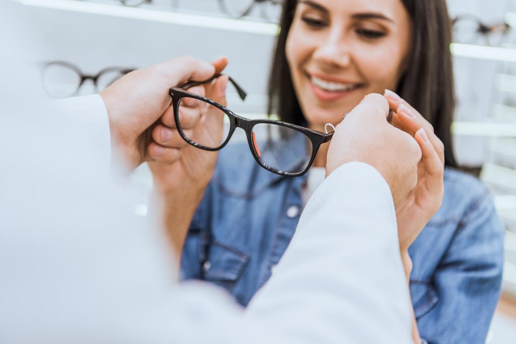 levágott kép a férfi szemész szakorvos, szemtréner szemüveg adva nő optika  - Fotó, kép