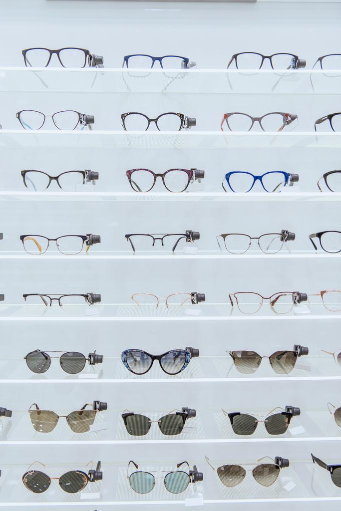 Полки со стильными очками и модными солнечными очками в офтальмологическом магазине
 - Фото, изображение