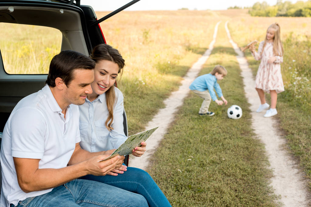 gelukkige jonge familie tijd samen doorbrengen in veld onderweg met de auto - Foto, afbeelding