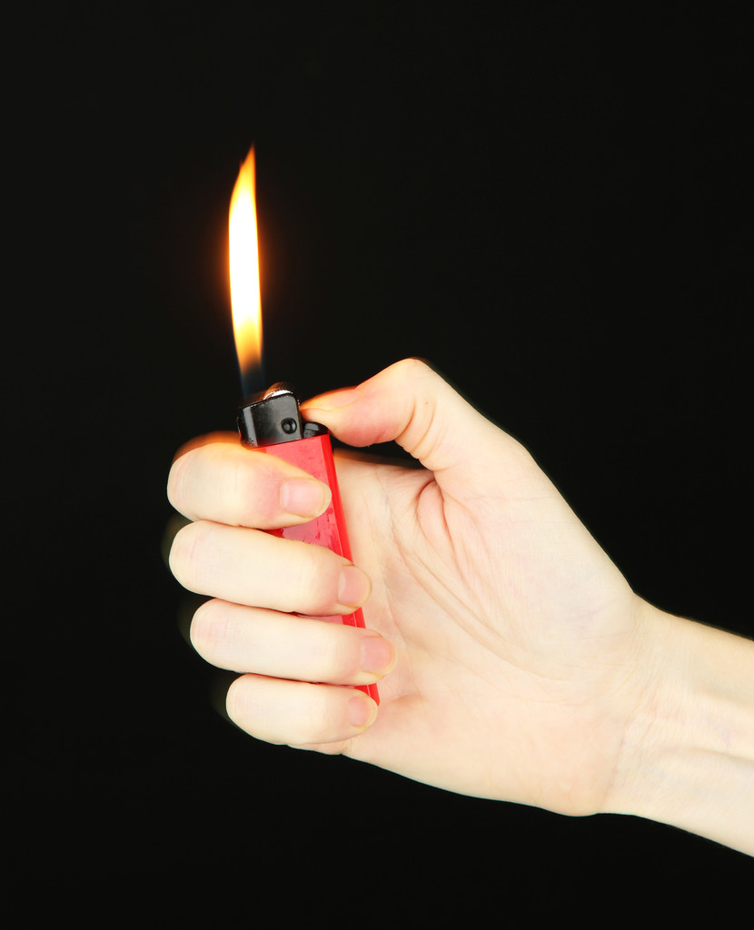 Горящая зажигалка в женской руке, изолированная на черном
 - Фото, изображение