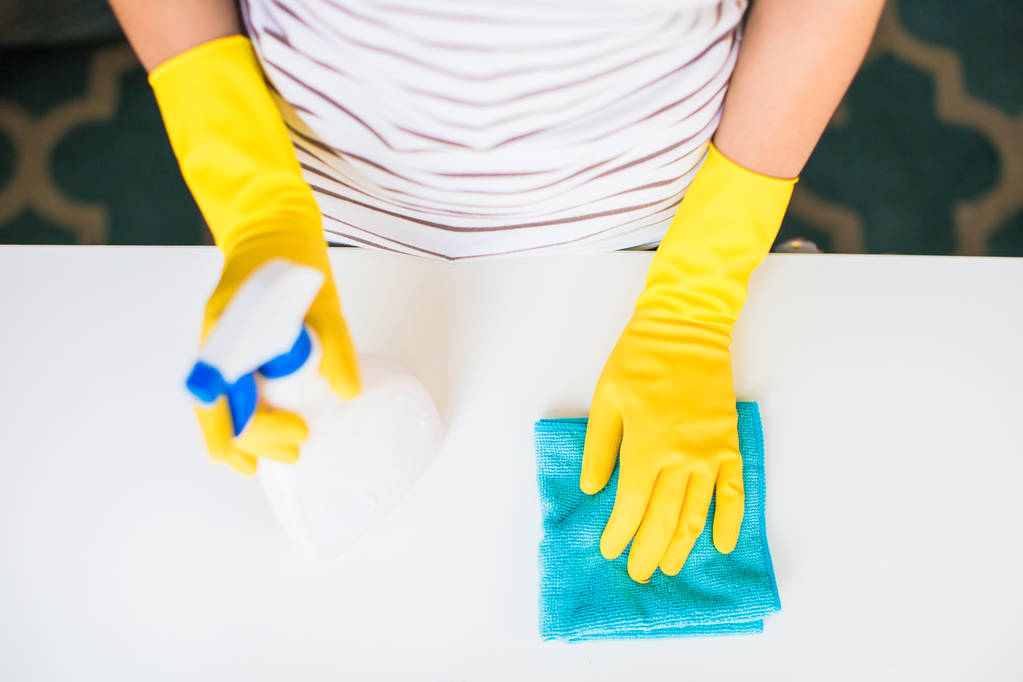 De jonge vrouw in gele handschoenen rag en venster schonere bedrijf in handen binnenshuis - Foto, afbeelding