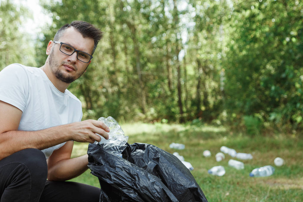 Lavora come volontario, volontario. Un volontario di sesso maschile che tiene un sacco della spazzatura raccoglie plastica. Concetto Pulizia della natura dalla plastica, inquinamento
. - Foto, immagini