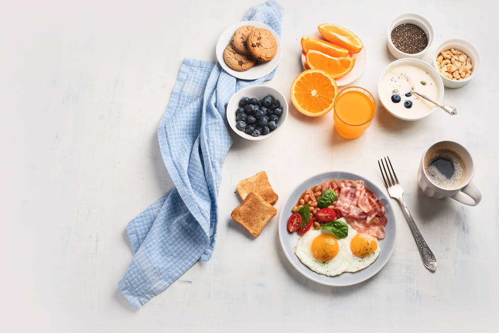 Café da manhã com ovos fritos, bacon, suco de laranja, iogurte e torradas. Vista superior com espaço de cópia
 - Foto, Imagem