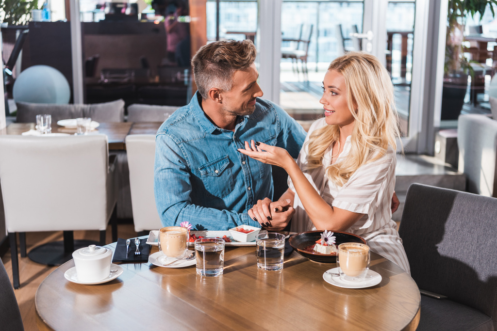 ευτυχισμένο ζευγάρι κρατώντας τα χέρια και να μιλάμε στο τραπέζι στην καφετέρια - Φωτογραφία, εικόνα