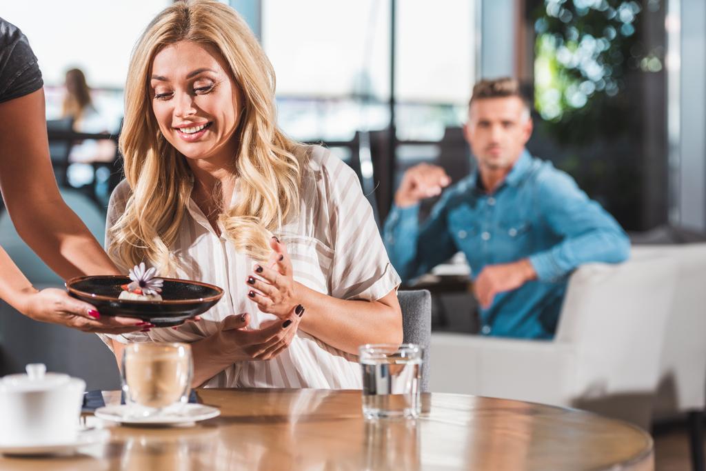 здивована щаслива жінка дивиться на десерт з квіткою в кафе
 - Фото, зображення