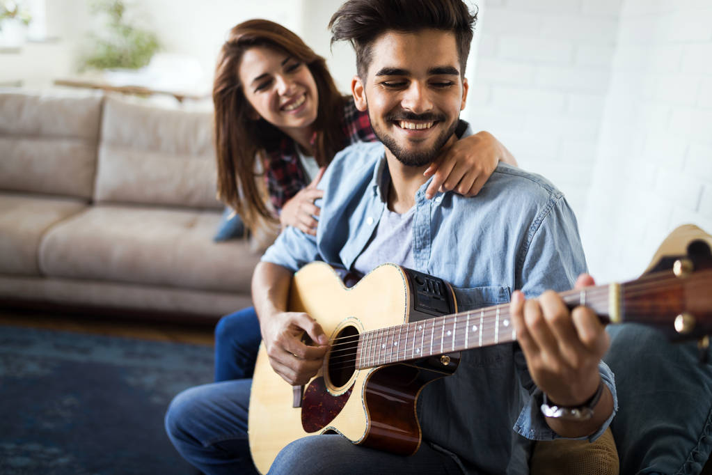 Joven hombre guapo tocando la guitarra para su hermosa novia - Foto, imagen