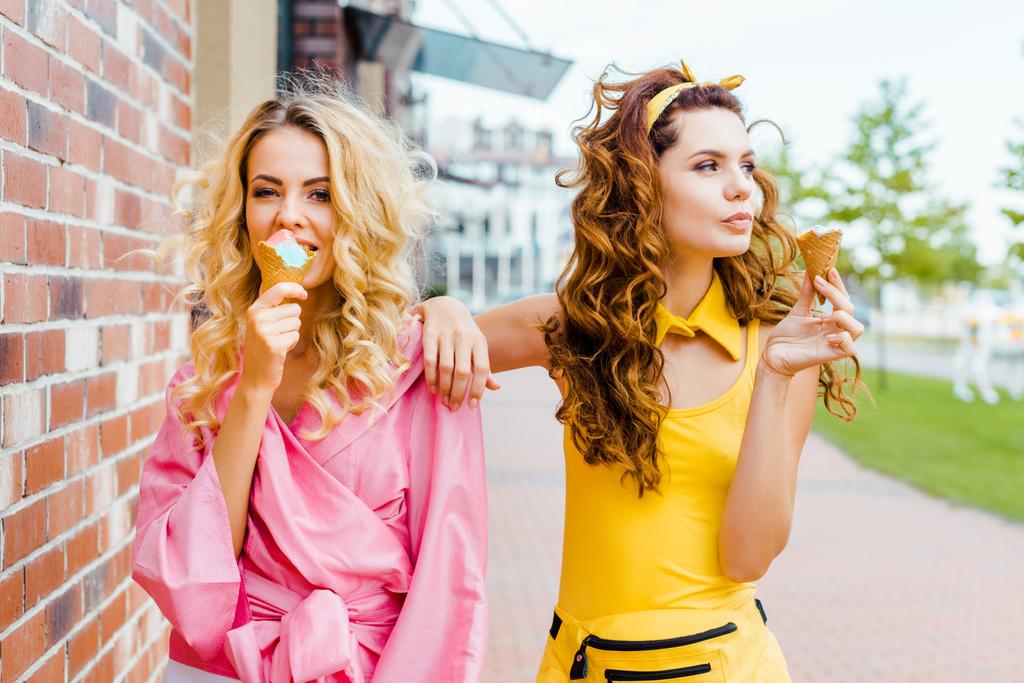 fashionable young women in colorful clothes eating ice cream on street - Photo, Image