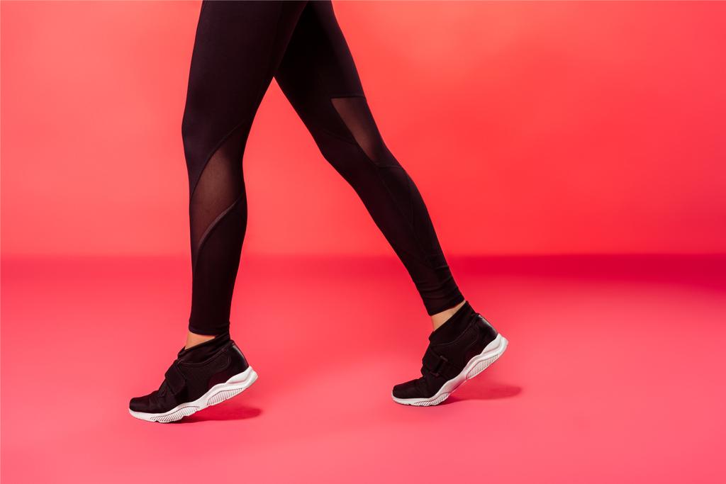 przycięte zdjęcie sportsmenka chodzenie w czarne legginsy na czerwono - Zdjęcie, obraz
