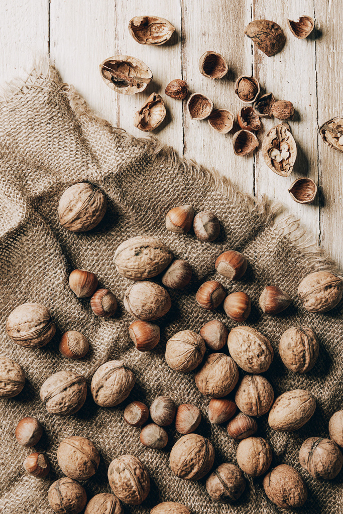 pohled shora lískové a vlašské ořechy na pytloviny na dřevěný stůl - Fotografie, Obrázek