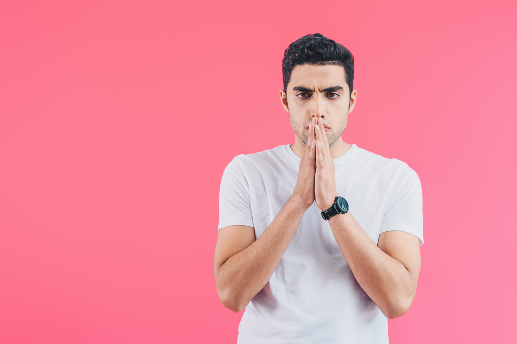 handsome man with hands in namaste gesture looking away isolated on pink - Photo, Image