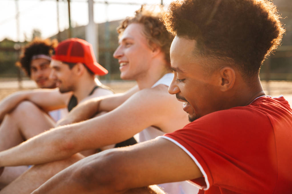 Groupe de jeunes hommes multiethniques heureux joueurs de basket-ball se reposant sur le terrain de sport, parler
 - Photo, image