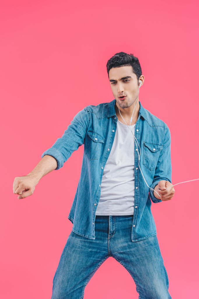 young emotional man in casual clothing and earphones dancing isolated on pink - Photo, Image