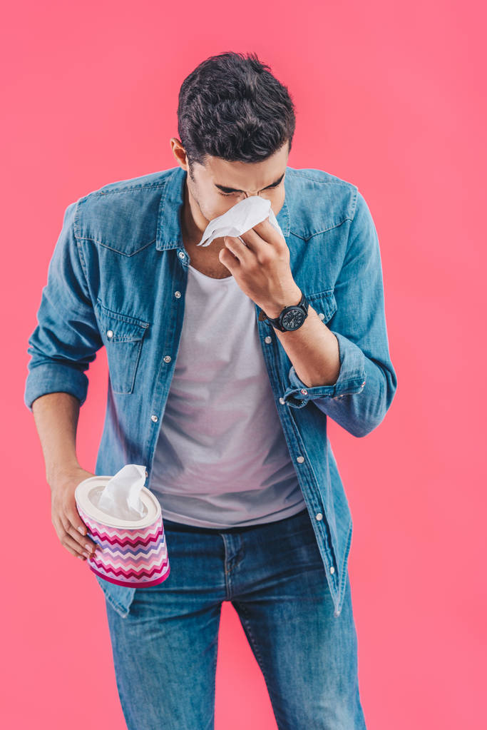 Junger Mann mit Gewebebox weint und wischt Nase isoliert auf rosa - Foto, Bild