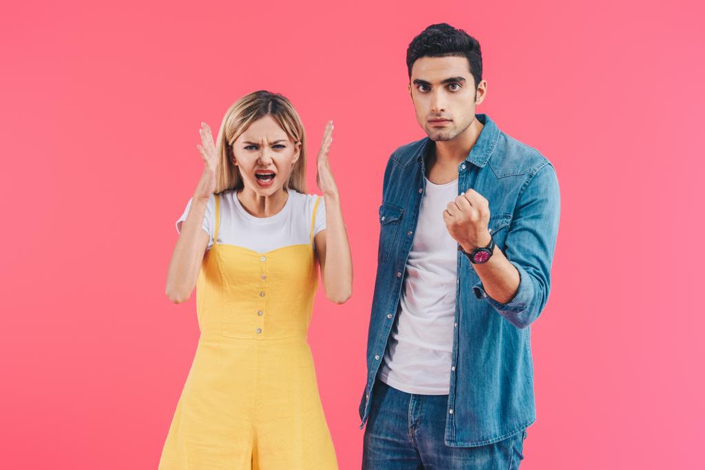 angry yelling woman gesturing by hands and her boyfriend threatening by fist isolated on pink  - Photo, Image