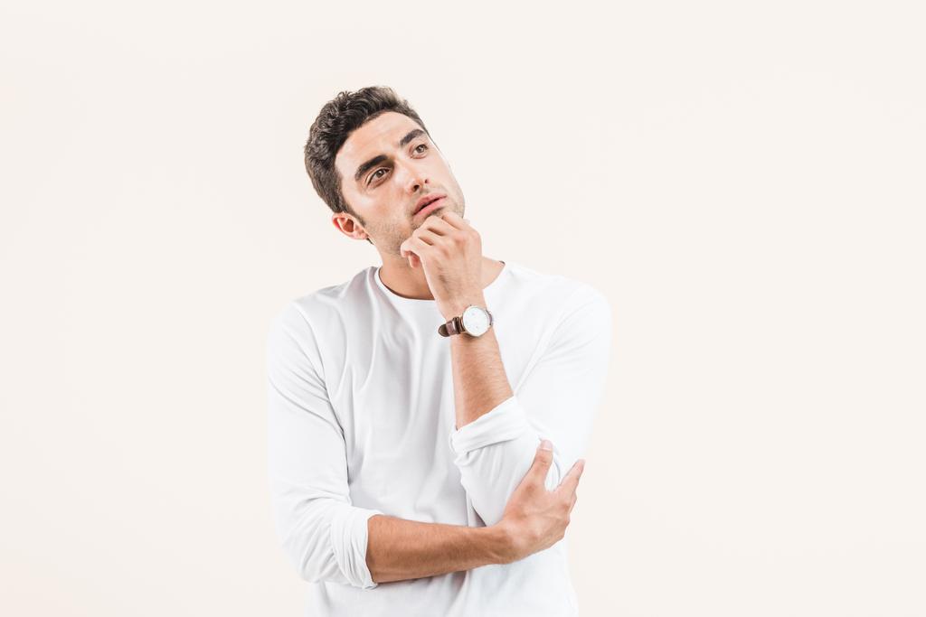 thoughtful young man with hand on chin looking away isolated on beige - Photo, Image