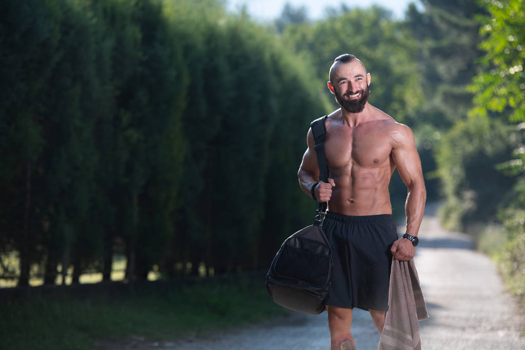 Homme barbu portant un sac de sport en plein air dans le parc et va au centre de remise en forme dans le gymnase
 - Photo, image