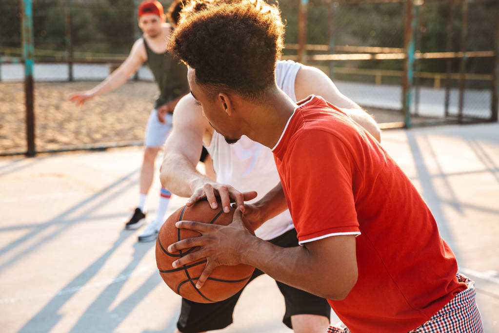 Retrato de chicos musculosos y deportivos jugando baloncesto en el patio de recreo al aire libre durante el día soleado de verano
 - Foto, imagen