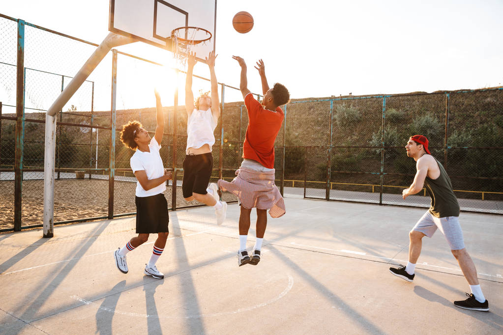 スポーティな多民族青年バスケット ボール選手のスポーツ地面でバスケット ボールをプレーのグループ - 写真・画像