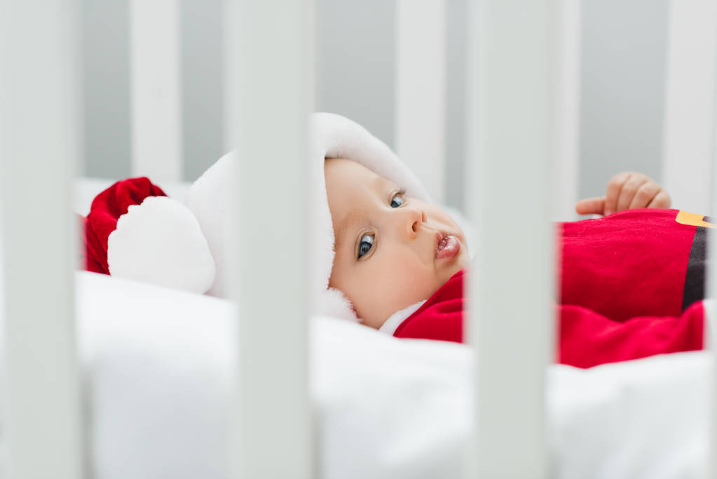 κοντά shot της όμορφο μωράκι σε santa κοστούμι ξαπλωμένη στο παχνί - Φωτογραφία, εικόνα