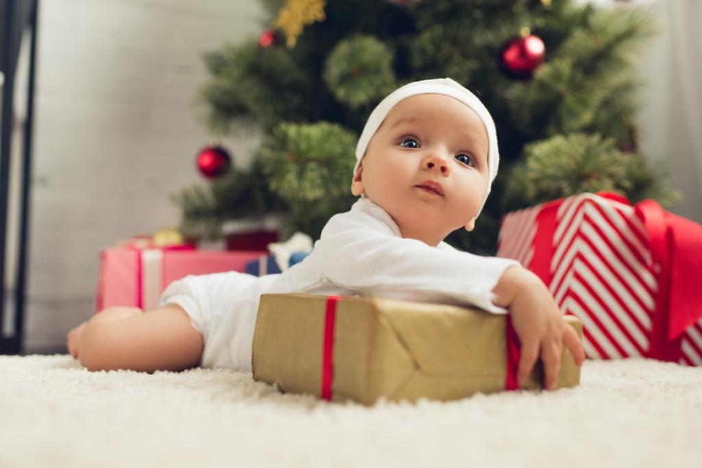 мила маленька дитина лежить на підлозі з різдвяними подарунками
 - Фото, зображення