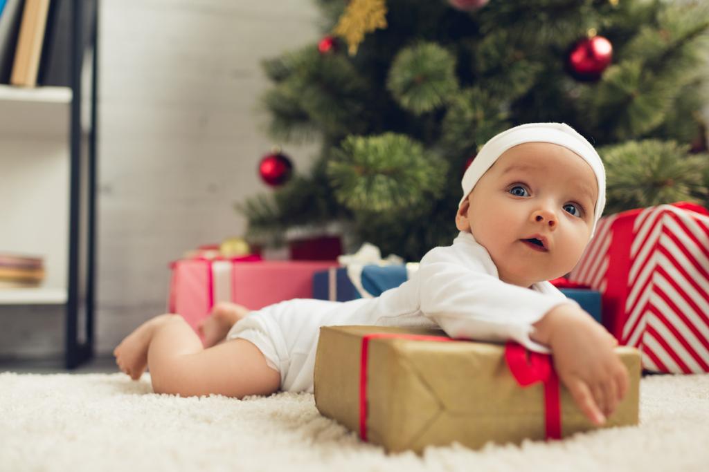 όμορφο μικρό μωρό ξαπλωμένο στο πάτωμα με τα δώρα Χριστουγέννων - Φωτογραφία, εικόνα