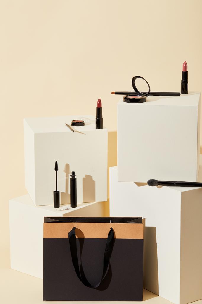 varios suministros de maquillaje acostado en cubos beige con bolsa de papel
 - Foto, imagen